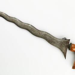Sword with engraved undulating blade. Engraved wooden pistol grip-style handle.