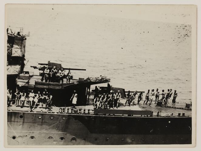 Group of seamen on standing deck of military ship.