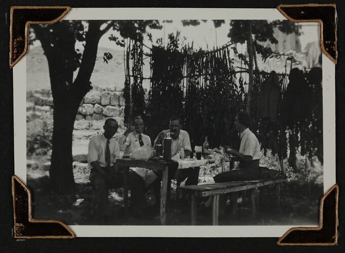 Four people sitting at a table in a garden.