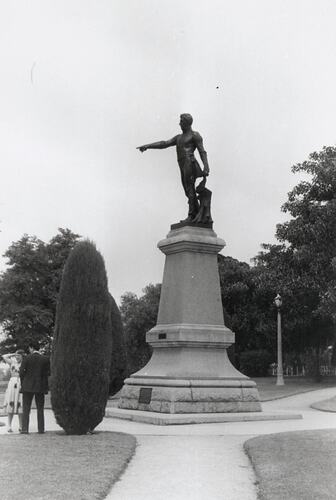 Bronze statue of man standing and pointing out to the distance. Mounted on dressed stone pedestal.