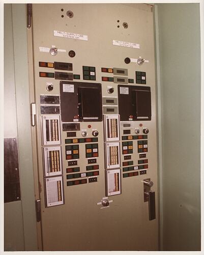 Control panel in wall with multi-coloured buttons.