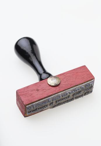 Red wooden stamp with black handle.
