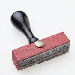 Red wooden stamp with black handle.