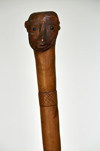 Carved wooden walking stick. Carved patterns and head on top. Head detail.