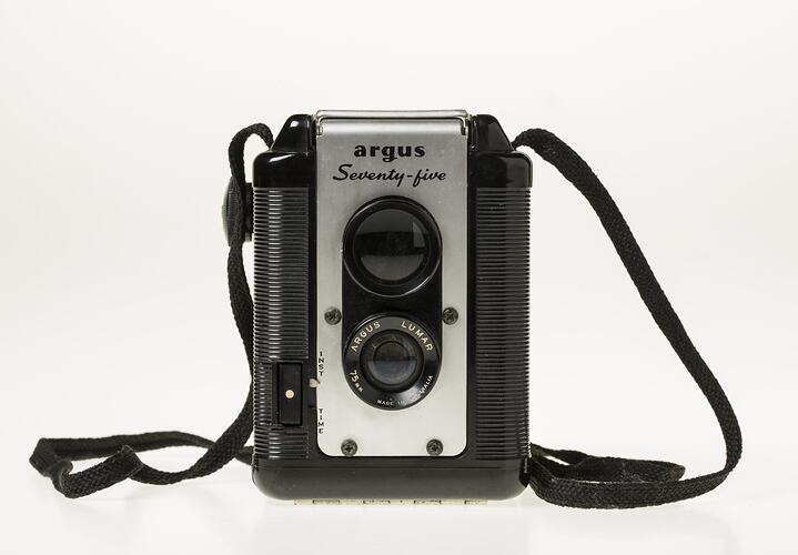 Box camera with black plastic body. Metal lens plate, black shoulder strap.