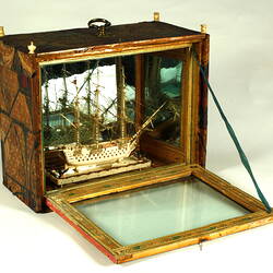 Model ship inside box with box window open.