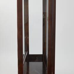 Wooden framed crystal cabinet. Glass doors and sides mirror at back. Side view, doors closed.