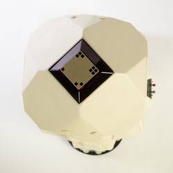 Top of view of cream plastic robot with angular human-like shape, ie. head, shoulders, waist and legs. Black plastic features.