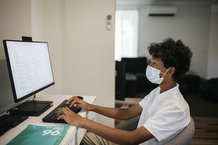 Kofi Aden Sits at Home Computer Wearing a Surgical Mask during the COVID-19 Pandemic, Roxburgh Park, Victoria, 25 November 2020