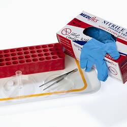 Laboratory equipment including forceps, vials, red vial tray, petri dishes, blue gloves.