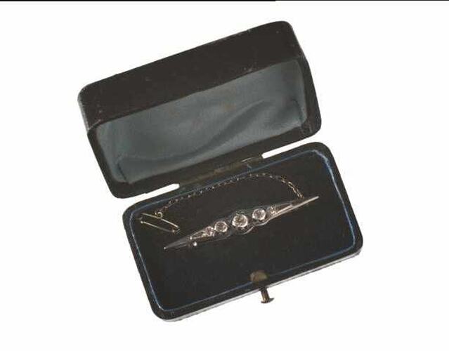 Diamond bar brooch in open box.