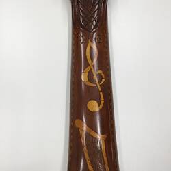 Detail of brown wooden mandolin neck with yellowish pattern.