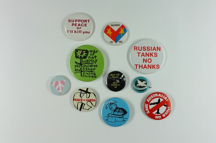 Mix of ten round coloured badges varying in size with words or images relating to peace.