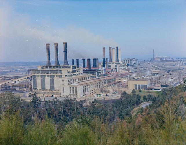 Skyline view of power station. Trees in foreground.
