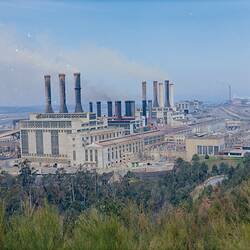 Skyline view of power station. Trees in foreground.
