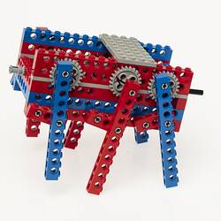 Red, blue and grey LEGO robot with three legs either side. Left profile.