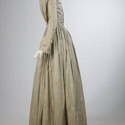 Pale grey striped silk dress with long sleeves and long skirt. Left profile.