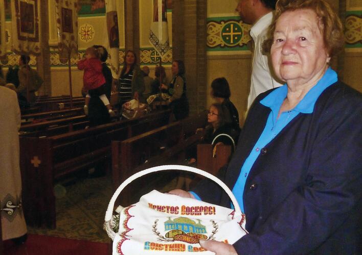 Woman holding a traditional Ukranian Easter basket covered with a hand-embroidered Easter cloth.