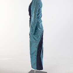 Aqua full-length sequin dress with navy swirls. Long sleeves, high neckline. Left profile.