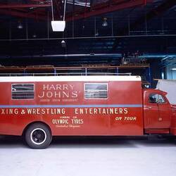 Motor truck with sign reading Harry Johns International Boxing Entertainers.