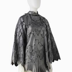 Short shift-style dress made from irregular pieces of pewter grey leather to resemble reptilian scales. Front right three quarter view.