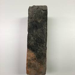 Soot blackened edge of red clay brick.