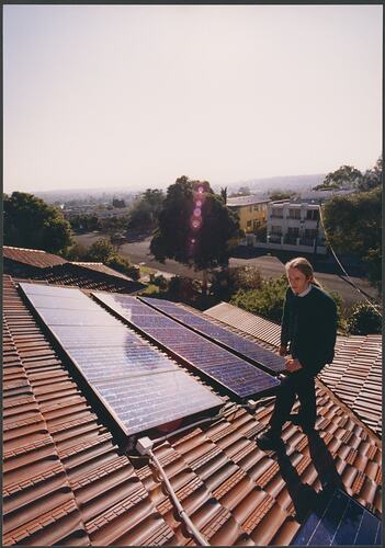 Man standing on rooftop with solar panels.
