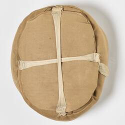 Top of beige cotton cap, padded, with strap.