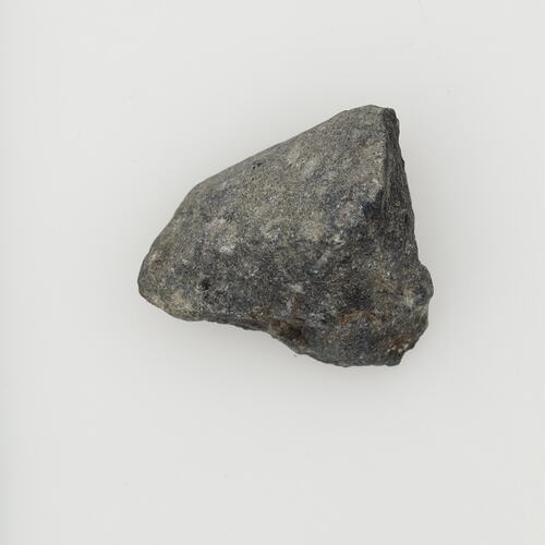 Triangular shaped dark grey stone. Rough surface.