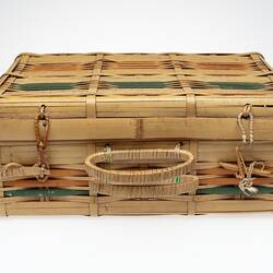 Split cane basket, hinge lid. Orange and green stripe detail. Two handles at front.