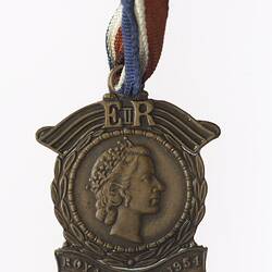Bronze medal with profile of a crowned woman surrounded by wreath, with banner and text.