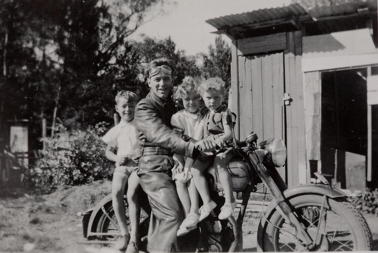 Digital Photograph - Man in Motorbike Leathers & Goggles, Balancing Children on Motorbike, Backyard, Ringwood East, circa 1957