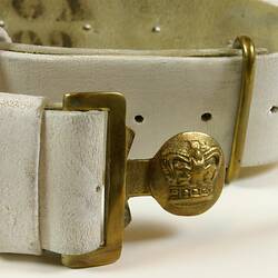 Detail of white belt showing brass buckle.