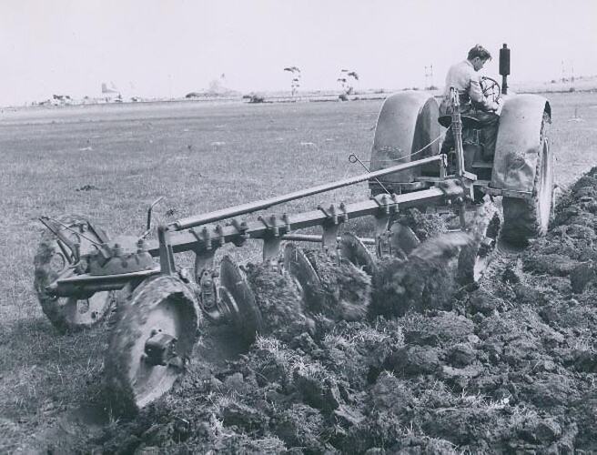 Man driving a tractor coupled to a disc plough.