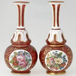 Pair of ruby red and white blown glass vases with gilt arabesque style tendril design, and enamelled floral panels.