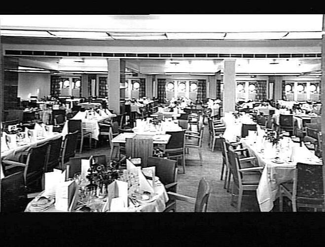 Ship interior. Dining area with tables set. Cutlery, menus, napkins, flowers.