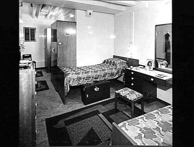 Ship interior. Two single beds against each wall. Dressing table in between.