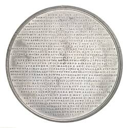 Round silver medal with 36 lines of raised text.