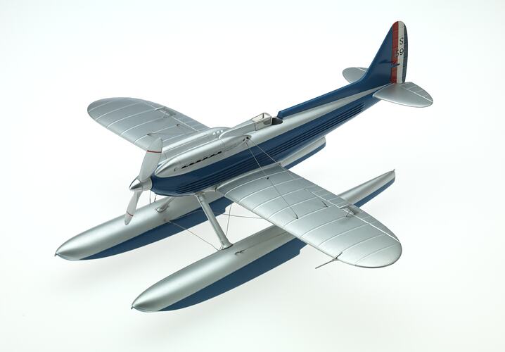 Plastic model aeroplane painted silver and blue with propeller at front. Three quarter front left view.