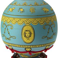 Blue wooden balloon model with yellow patterns. Basket base holds figurines. Side A.