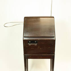 Front view of theremin in wooden case on legs.