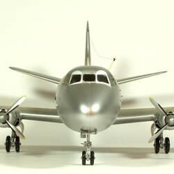 Silver model aeroplane with two propellers on each wing. Front view.
