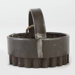 Metal pastry cutter with round serrated edge and handle. Side view.