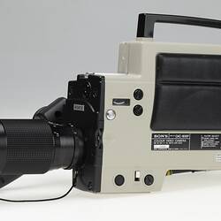 Side view of black and beige video camera with handle.