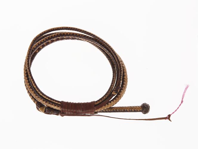 Hat band made as leather braided miniature whip with handle, thong and pink fabric tip. The band is looped.