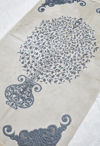 Cream prayer mat with blue print and embroidered design. Detail on central motif.