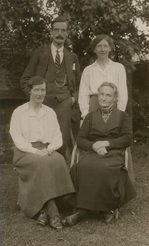 Group portrait with man, one woman standing and two seated women in front.