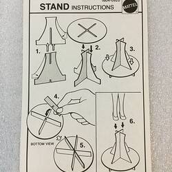Paper with printed diagram of assembly instructions for Barbie doll stand.