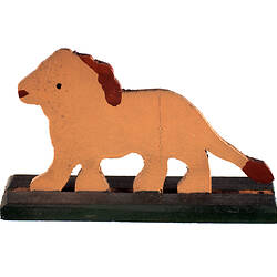 Side view of painted light brown wooden toy lion on black stand.