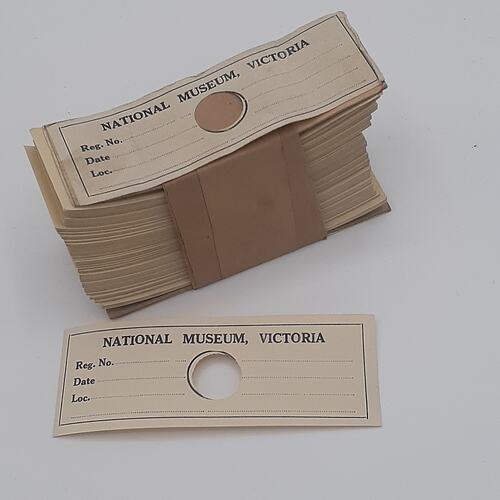 A bundle of rectangular paper labels with a small circular cut out in the middle of each.